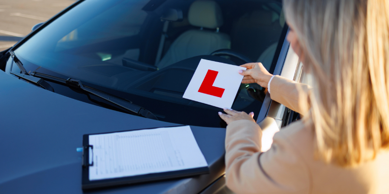 Woman placing l-plates onto a car windscreen