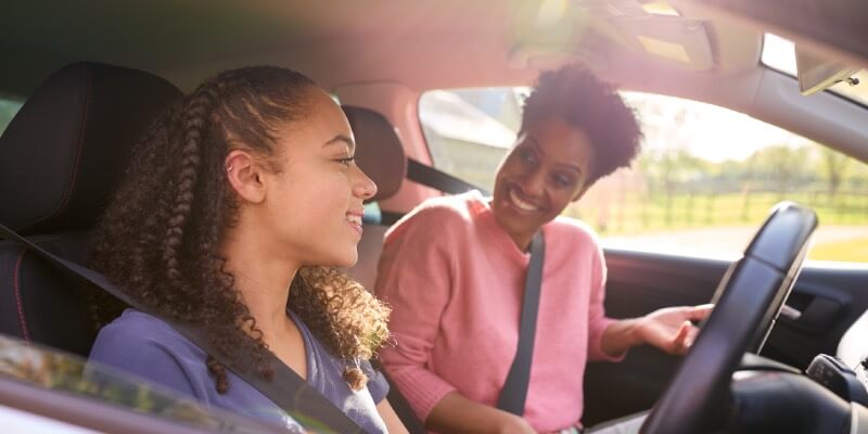 Two women in the car smiling at each other