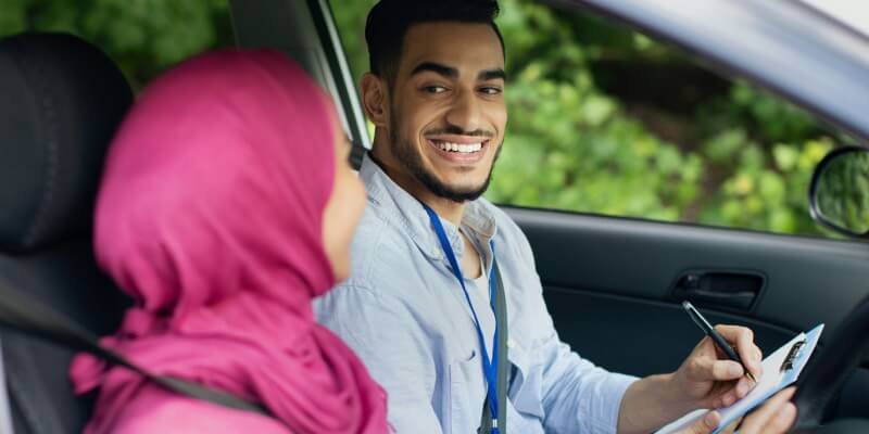 Examiner and girl smiling at each other inside car