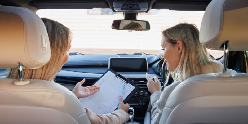 Learner and instructor looking at clipboard in car